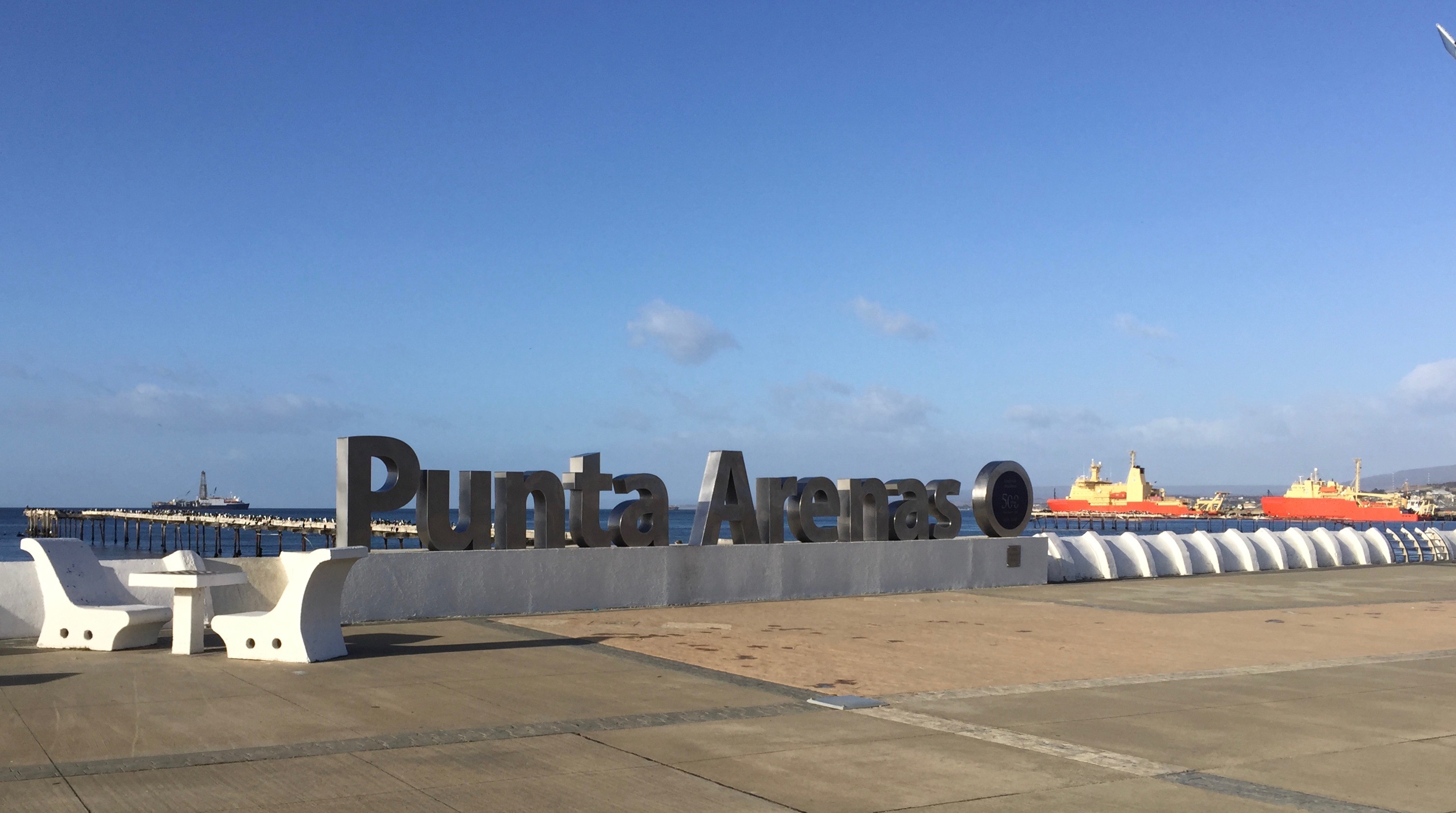 Three ships at anchor with the Punta Arenas sign in the foreground