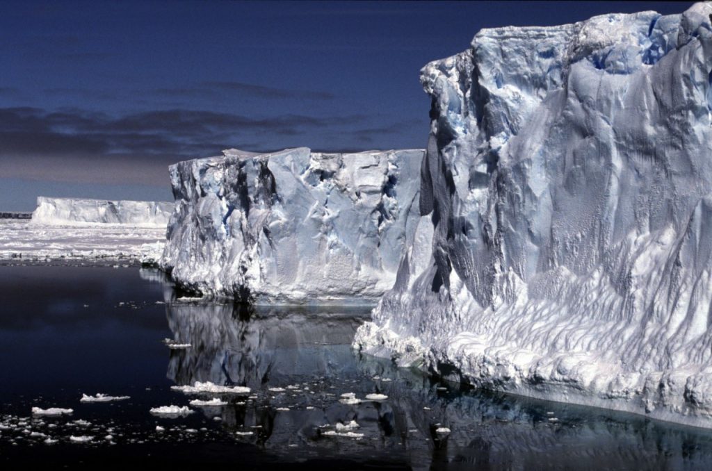 Ice shelf towering above dark, calm water