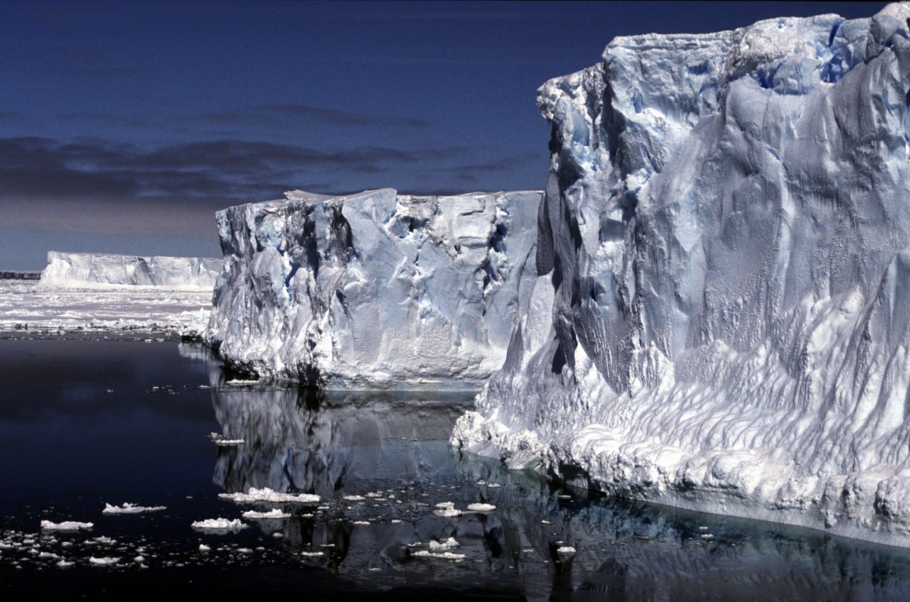 A wall of ice towers above a dark, calm sea