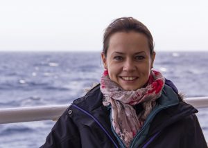 Dr. Linda Armbrecht smiles at the camera with the ocean behind her.