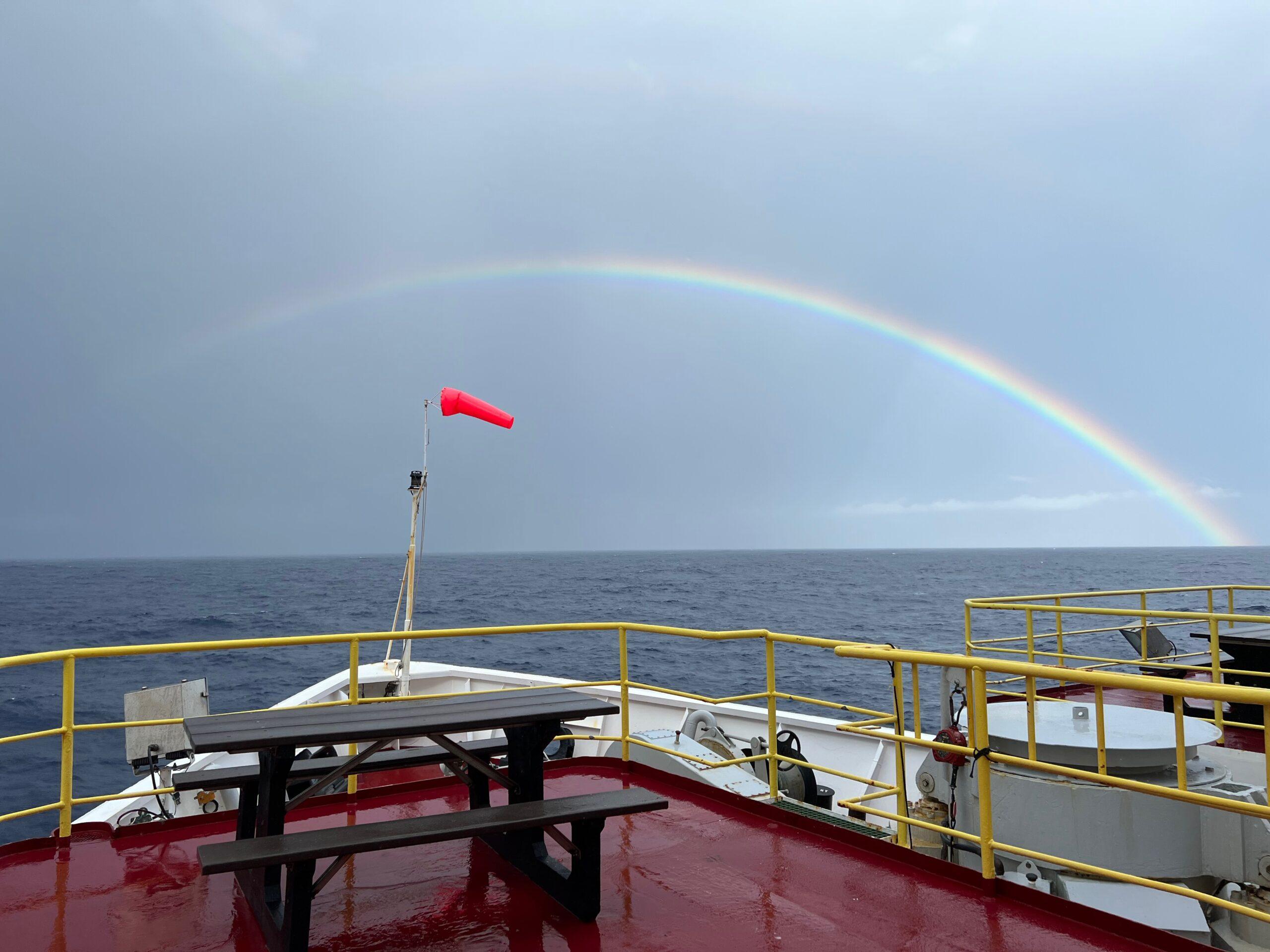 rainbow past bow of ship on water