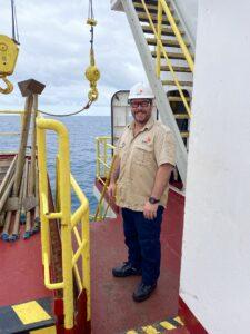 Glenn stands just off the rig floor, with the ocean in the background.