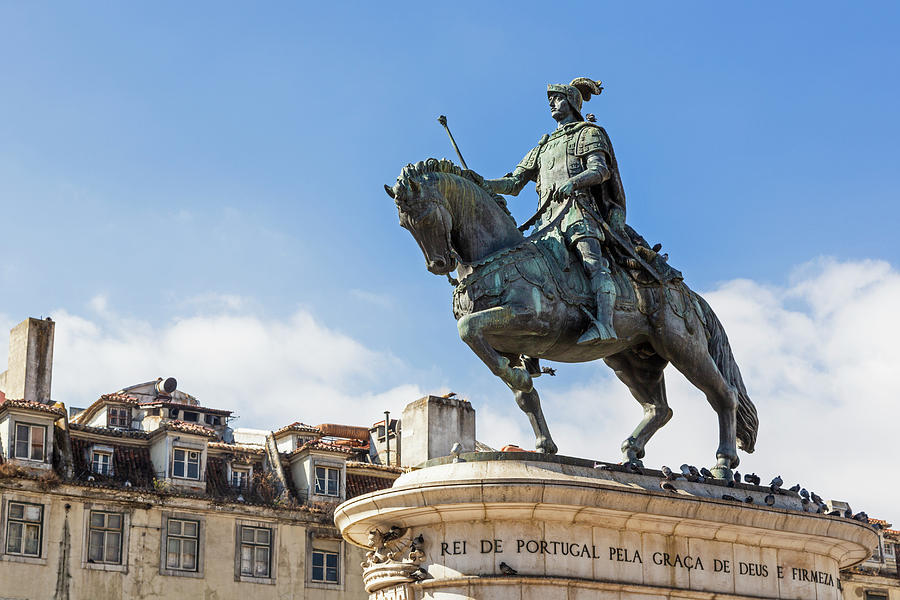 A bronze statue of Dom João I riding a horse with blue sky in the background.