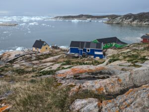 Colorful buildings along a harbor with icebergs floating in the harbor