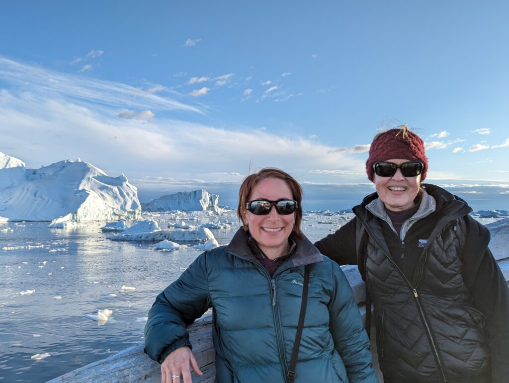 Two women on a boat in front of icebergs in Greenland