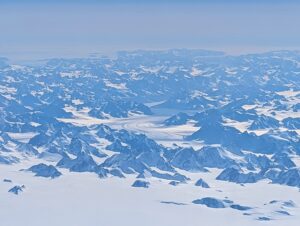 Flying over the Greenland Ice Sheet with glaciers, mountains, and the ocean also in view