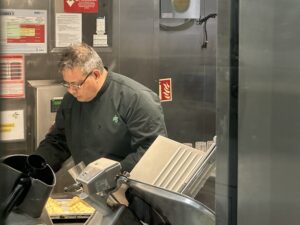 Chef in black jacket working at a table.