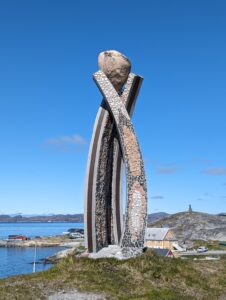 Statue with three curved posts holding a ball above a harbor in Greenland