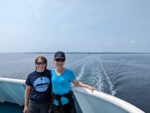 Two women on a ferry with the wake from the boat in the background