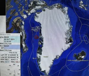 A map showing the location, as the red circle of a ship off the coast of northwest Greenland. The sea is colored in blue and Greenland is mostly white. Surrounding land is mostly green.