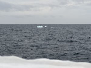 A small iceberg sits on a gray sea. Because it sits less than 1 meter above the water, it is called a "growler." 
