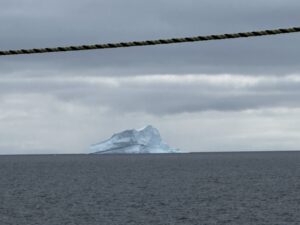 A small iceberg sits on a gray sea. Because it sits less than 1 meter above the water, it is called a "growler." 