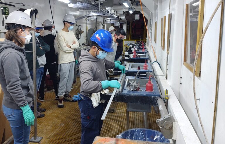 People stand behind technicians as the process a core laid horizontally